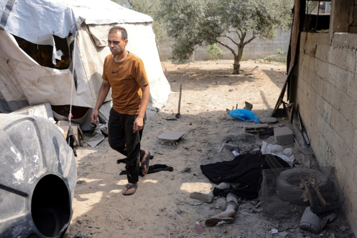 Un Palestinien passe près du coprs d'un victime d'une frappe israélienne sur le quartier Abou Iskandar dans le nord de Gaza-ville, pilonnée par l'armée israélienne avant une offensive annoncée au sol, le 22 août 2025