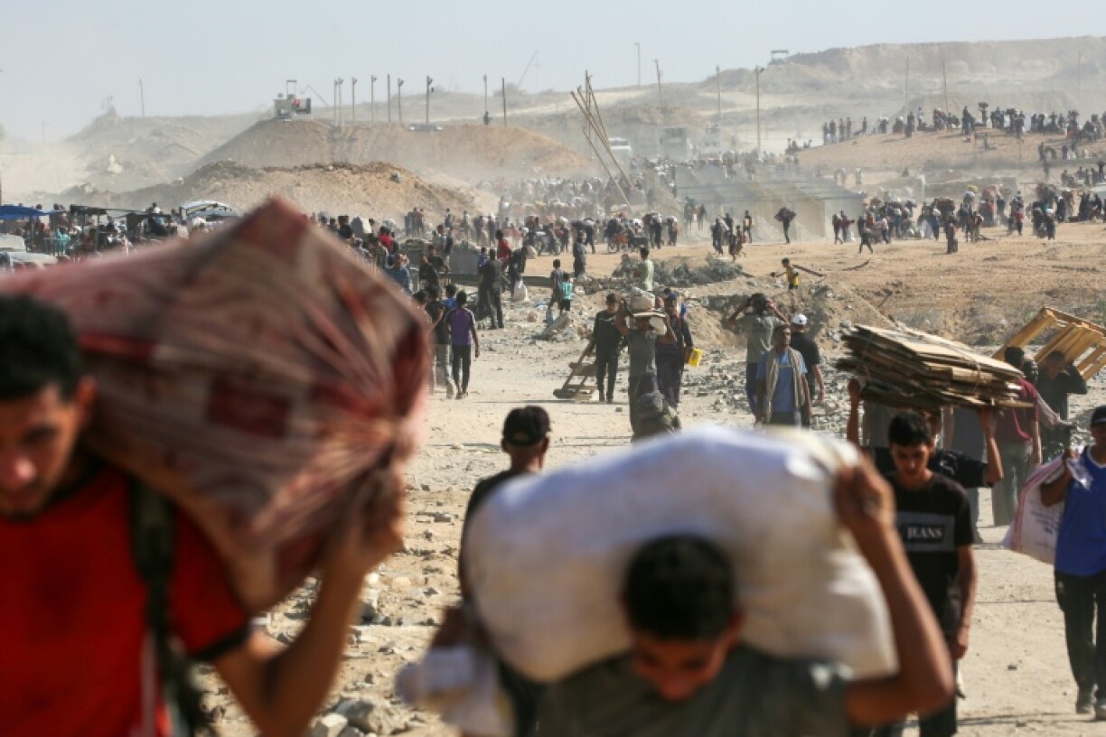Des Palestiniens marchent avec des sacs d'aide humanitaire distribuée par la Gaza Humanitarian Foundation (GHF), à Nuseirat dans la bande de Gaza le 26 septembre 2025