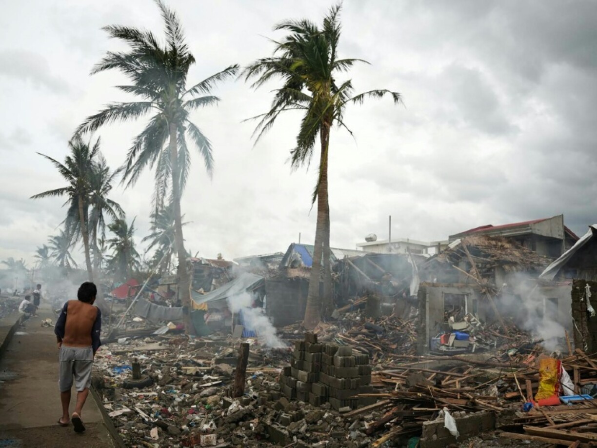 Residents burn wood from their destroyed homes near the seawall at Garchitorena in the Philippines' Camarines Sur province