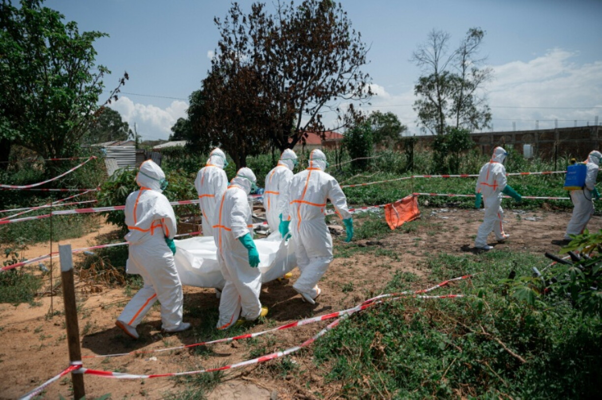 Des bénévoles de la Croix-Rouge, en combinaison de protection, transportent le corps d'une victime de la maladie à virus Ebola au centre de santé de Rwampara, le 8 juin 2026 en RDC
