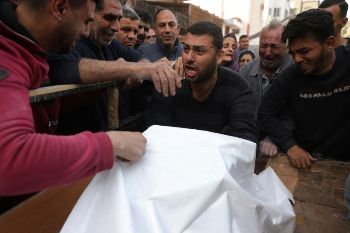 Palestinian men weep around a covered body before its burial following overnight Israeli strikes on Jabalia in northern Gaza