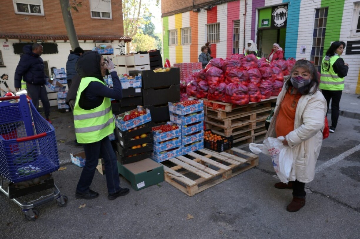 Une habitante cherche de la nourriture devant le local de l'association du quartier Aluche à Madrid, le 19 novembre 2022