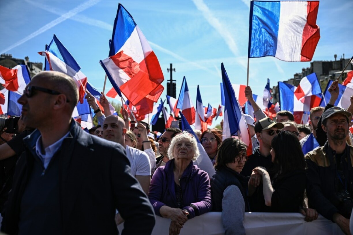 Des manifestants arborent des drapeaux français lors d'un rassemblement de soutien à la présidente du groupe parlementaire du Rassemblement national (RN), Marine Le Pen, le 6 avril 2025 à Paris