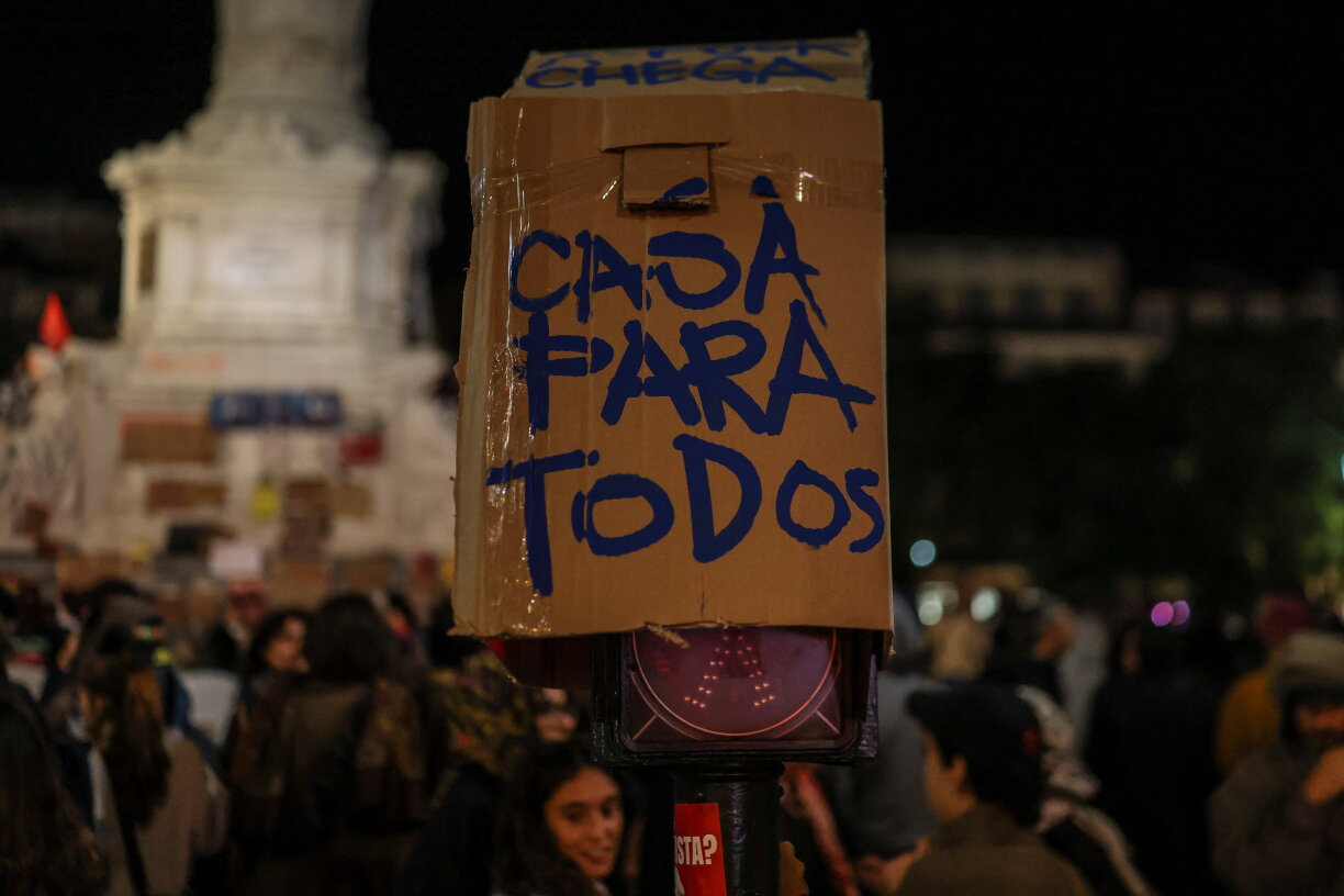 Une affiche portant l’inscription « Un logement pour tous » est visible sur un campement installé pour protester contre la pénurie de logements, la flambée des loyers et les bas salaires, sur la place du Rossio, dans le centre de Lisbonne, dans la soirée du 19 octobre 2026.