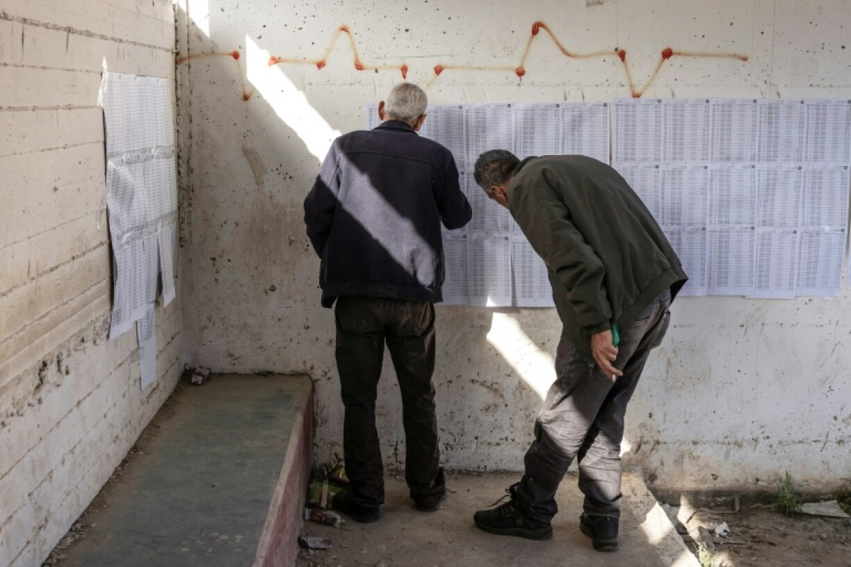 Deux hommes consultent les listes électorales dans un bureau de vote lors des élections municipales du village de Qabatiyah, au sud de Jénine, en Cisjordanie occupée par Israël, le 25 avril 2026