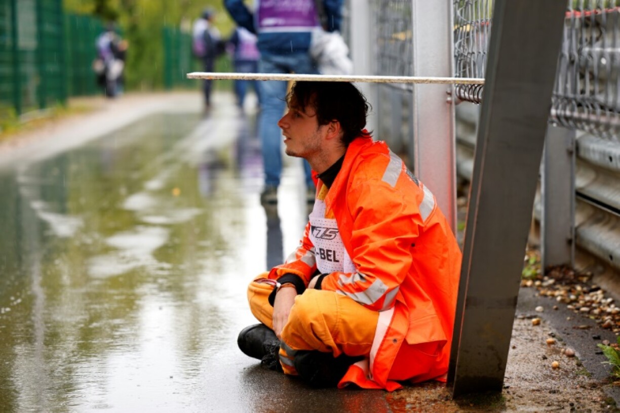 A marshall shelters from the rain as the start of the Formula One Belgian Grand Prix at the Spa-Francorchamps circuit was delayed for 80 minutes