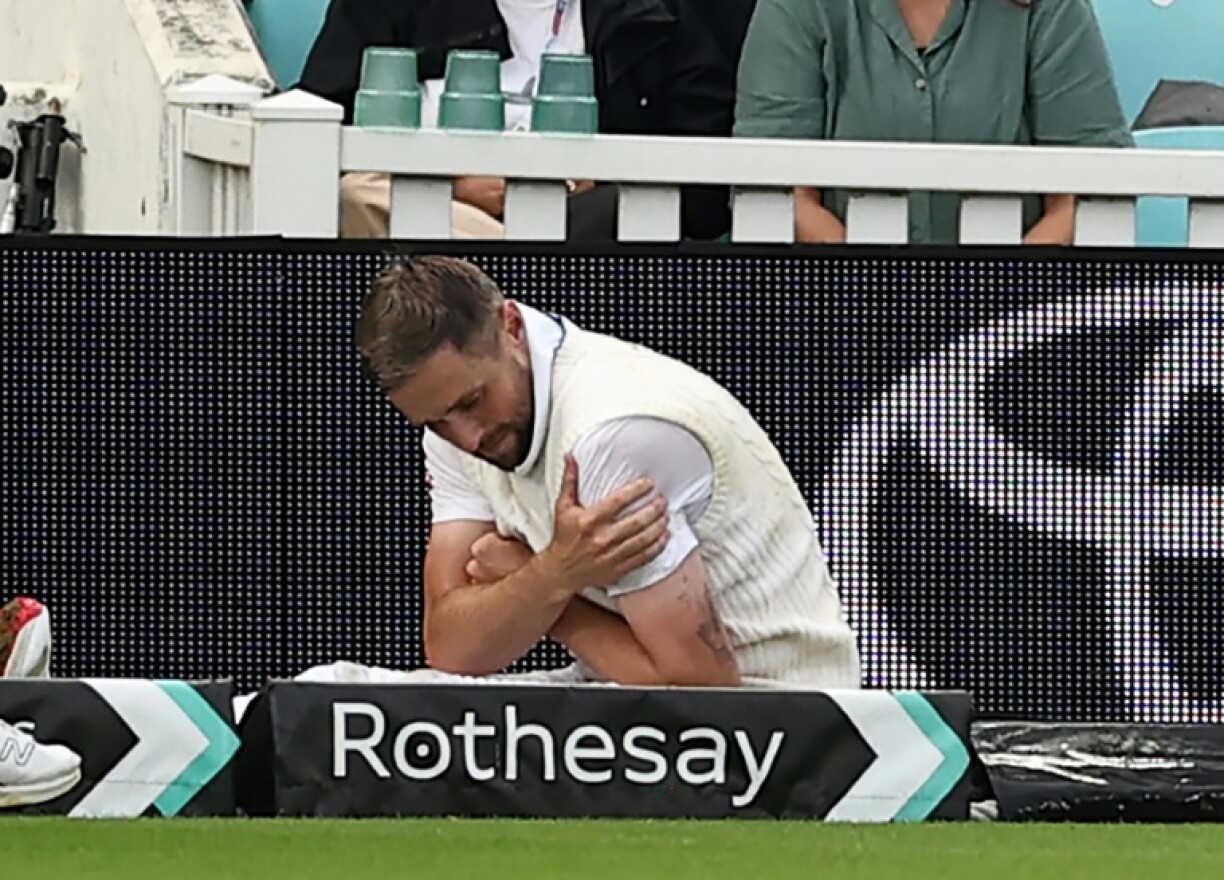 England's Chris Woakes holds his shoulder after falling over at the boundary during the fifth Test against India at the Oval
