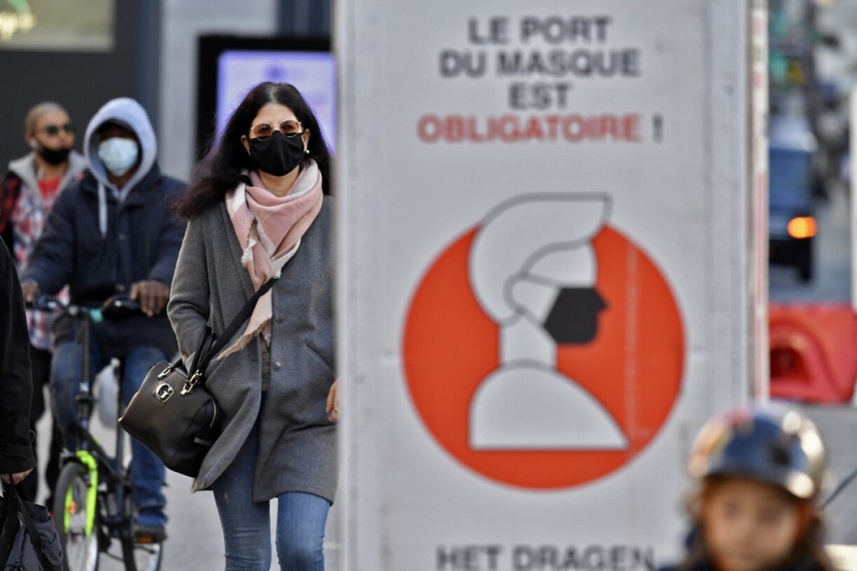 Des passants devant un panneau rappelant le port du masque obligatoire à Bruxelles.
