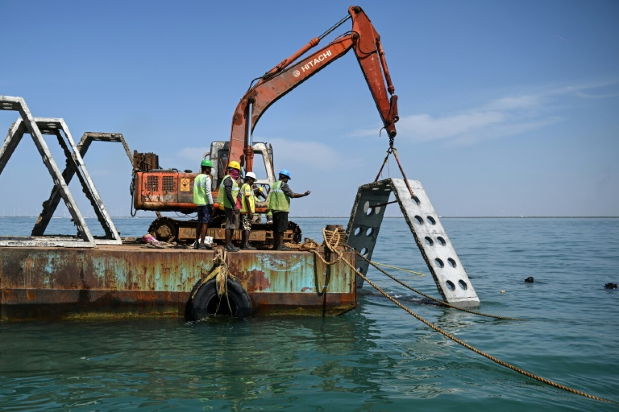 Workers shift artificial reef modules using a barge into the designated deployment layout near Kariyachalli Island, off the coast of Thoothukudi in India's Tamil Nadu state