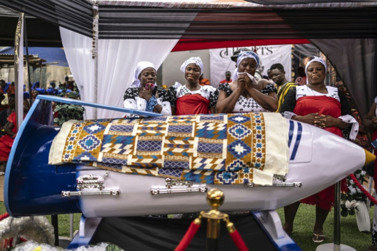 Des proches pleurent près du cercueil en forme de stylo de Samuel Commey Tetteh, enseignant ghanéen décédé, lors de ses funérailles à Paanor, au Ghana, le 15 août 2026