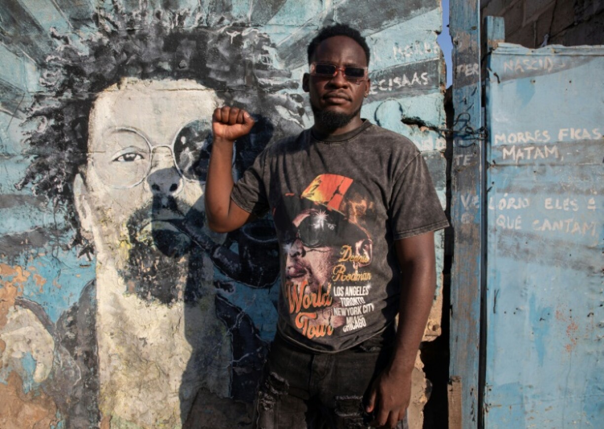 Mozambique rapper Nikotina poses next to a mural of his idol, social issues rapper Mano Azagaia