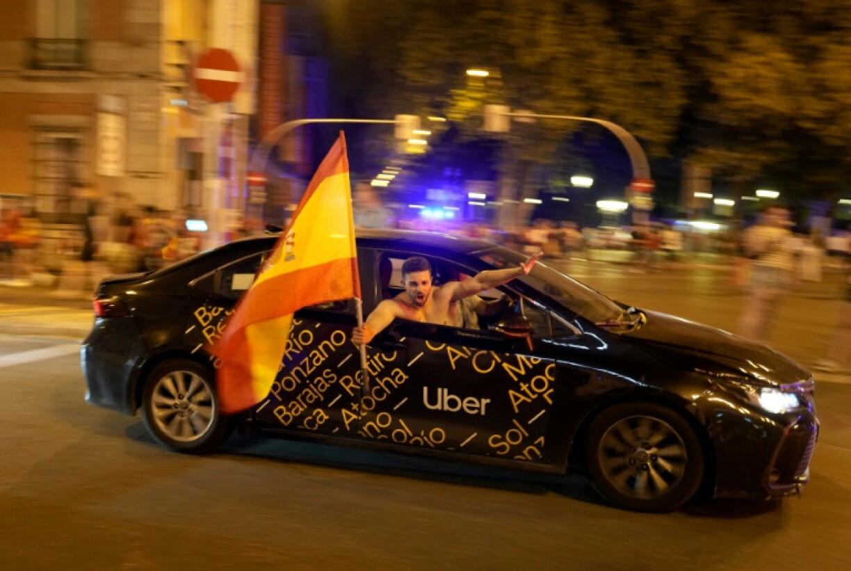 Un supporter agite un drapeau de l'Espagne dans un taxi à Madrid le 19 juillet 2026 après la vicoire de la Roja en finale de la Coupe du monde