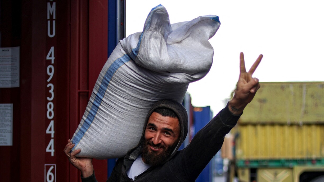 A worker flashes the V for victory sign as he unloads goods from a container at the mediterranean port of Latakia in western Syria on 30 December.