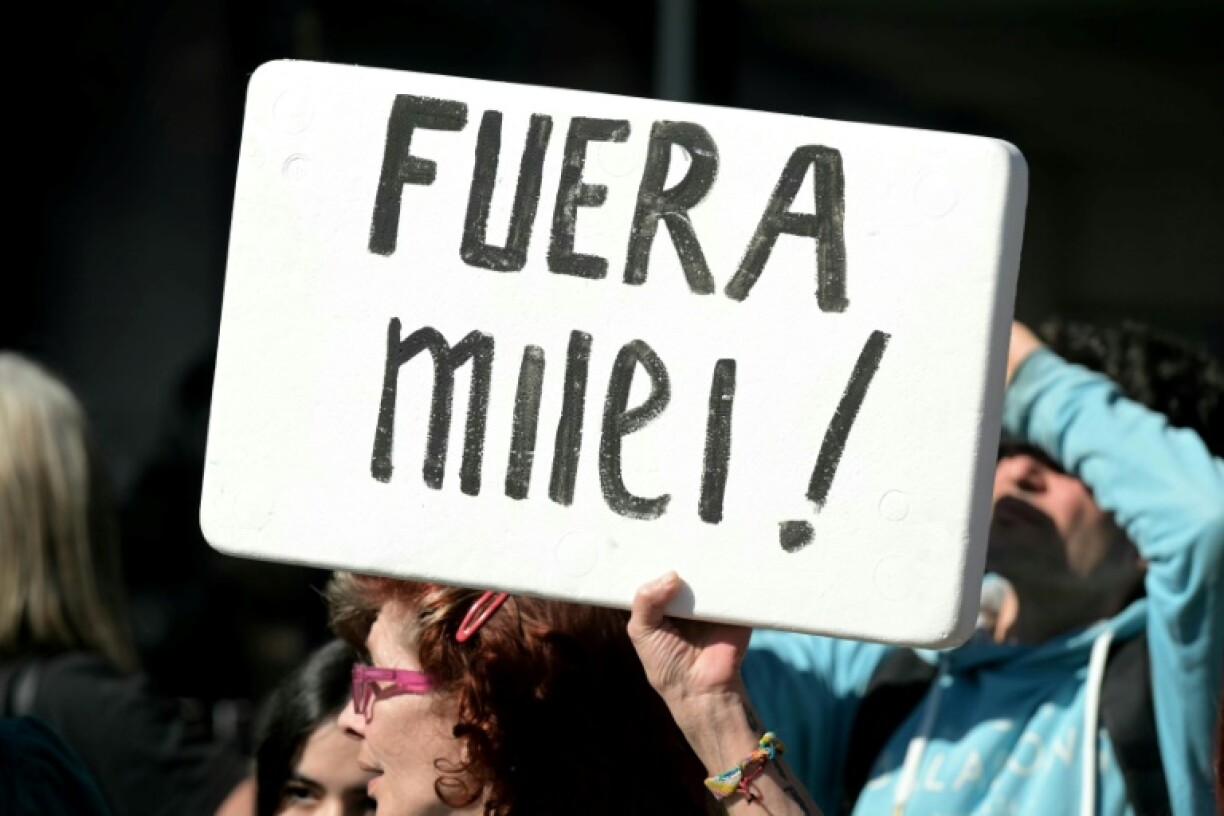 An anti-government protester holds a banner reading 'Milei out!' during a campaign event by Argentine President Javier Milei on the outskirts of Buenos Aires, at which he was pelted with stones