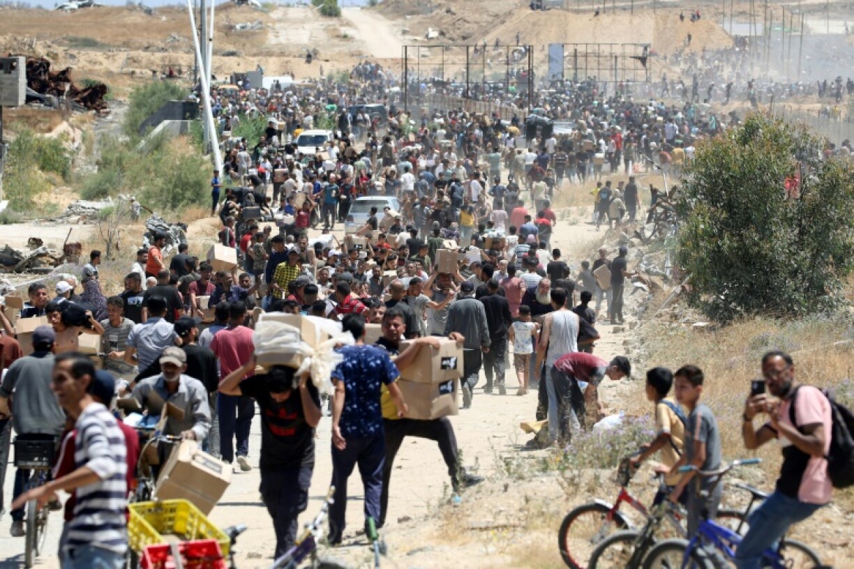 People carry boxes of relief supplies from the Gaza Humanitarian Foundation at adistribution center in the central Gaza Strip