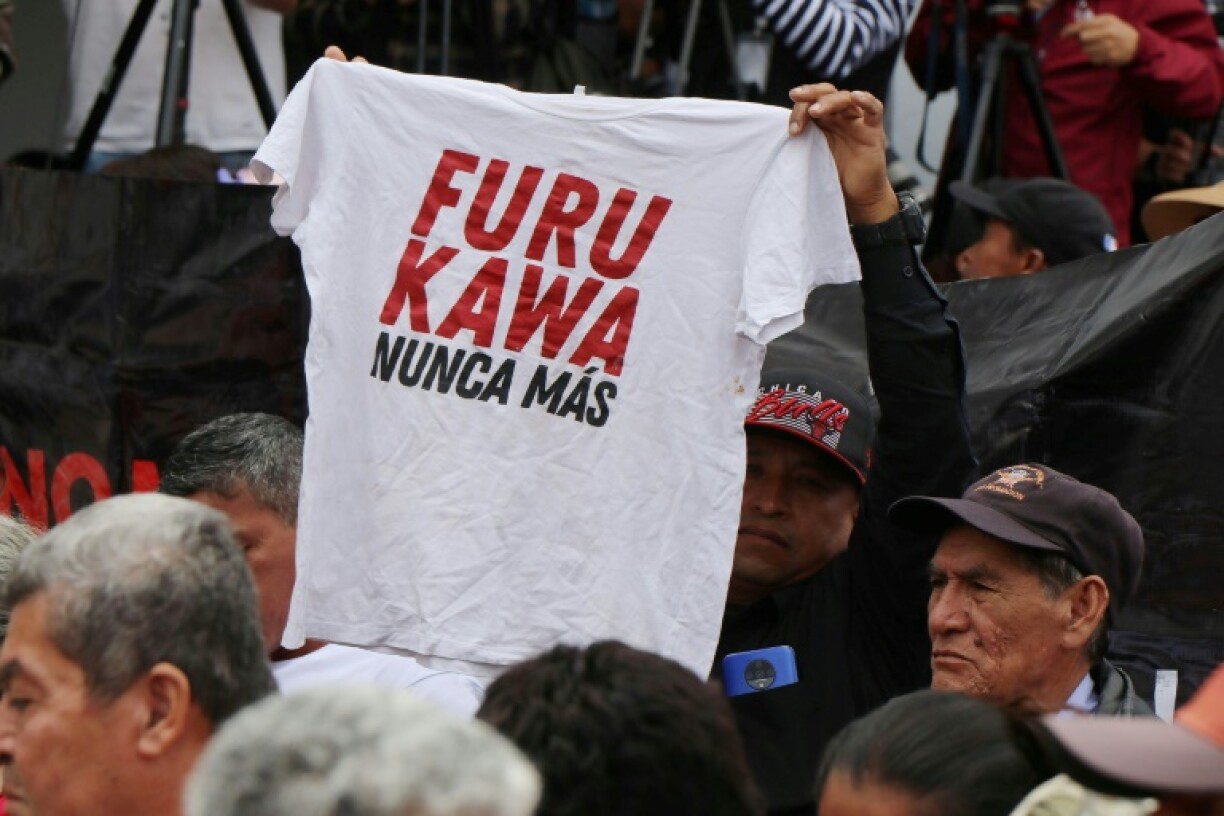 A man in Ecuador holds up a shirt with the slogan 'Furukawa, never again,' alluding to a Japanese textile firm found to have abused its workers