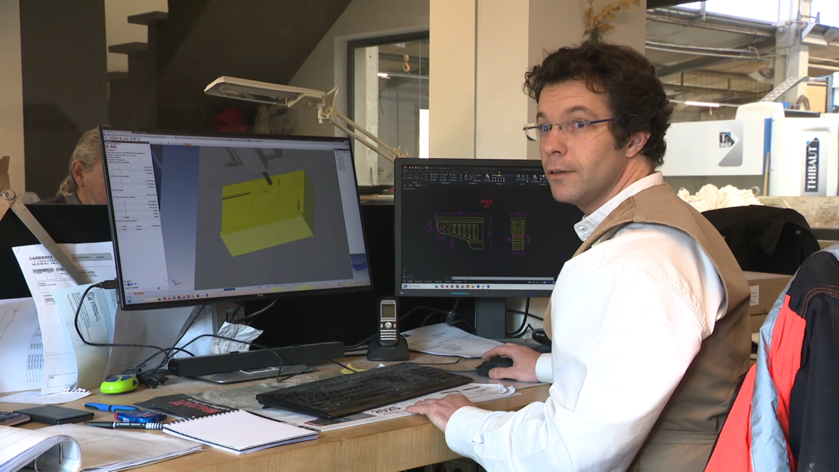 Henri-Louis David devant les écrans où il façonne numériquement un "corbeau" en pierre.