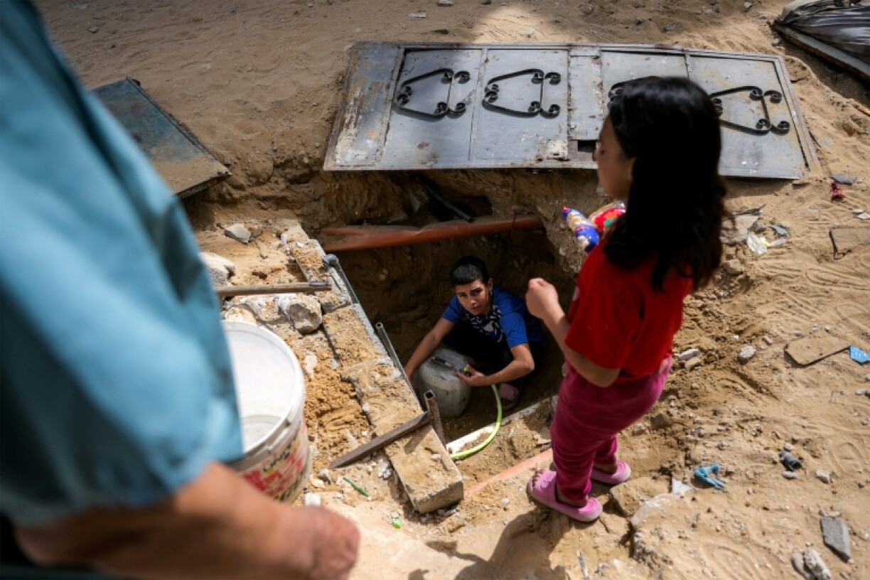 Un garçon puise de l'eau restant dans des canalisations souterraines, à Beit Lahia, dans le nord de la bande de Gaza, le 24 avril 2025