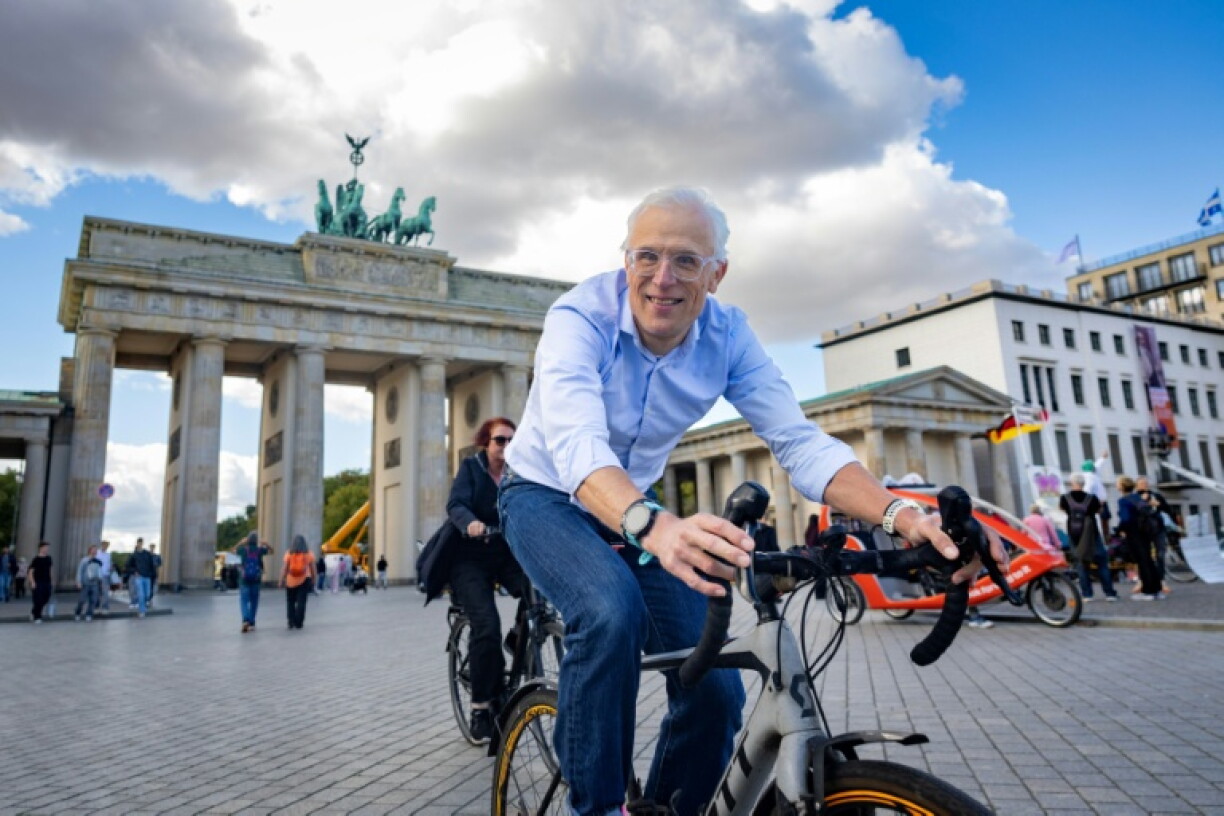 Claus-Henning Schulke, known as 'Bottle Claus', poses for photos on his bicycle in front of Berlin's landmark Brandenburg Gate.