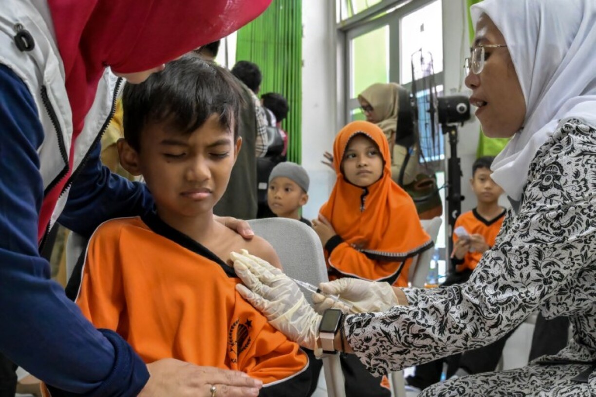 A healthcare worker administers the measles vaccine to an elementary school student during the launch of a free health check programme for children, in Jakarta on August 4, 2025.