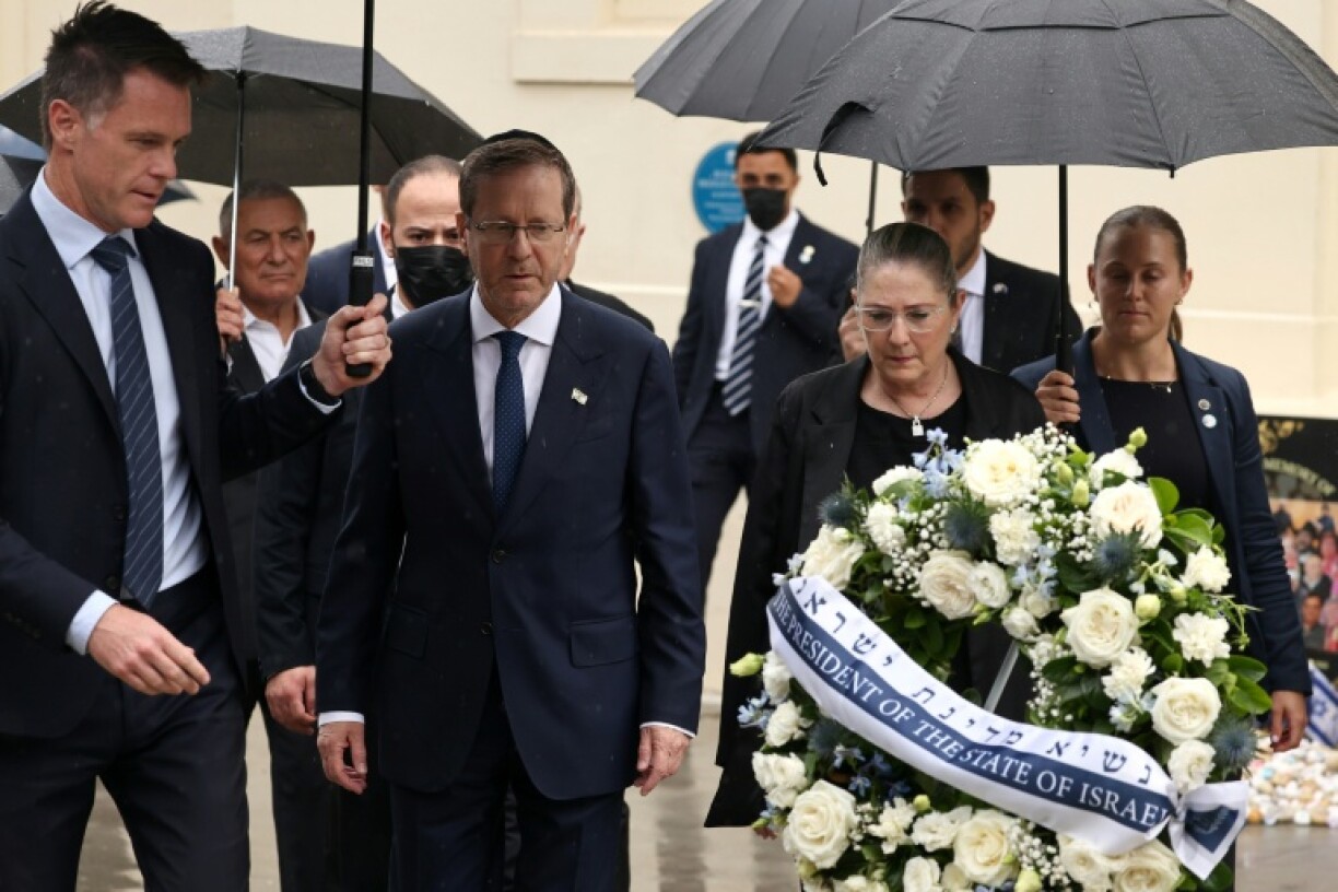 Le président israélien Isaac Herzog (c) et son épouse Michal (2e d) accompagnés par le Premier ministre de Nouvelle-Galles du Sud, Chris Minns (g), déposent une gerbe en hommage aux victimes de l'attaque du 14 décembre 2025 au Bondi Pavilion, à Sydney, le 9 février 2026 en Australie
