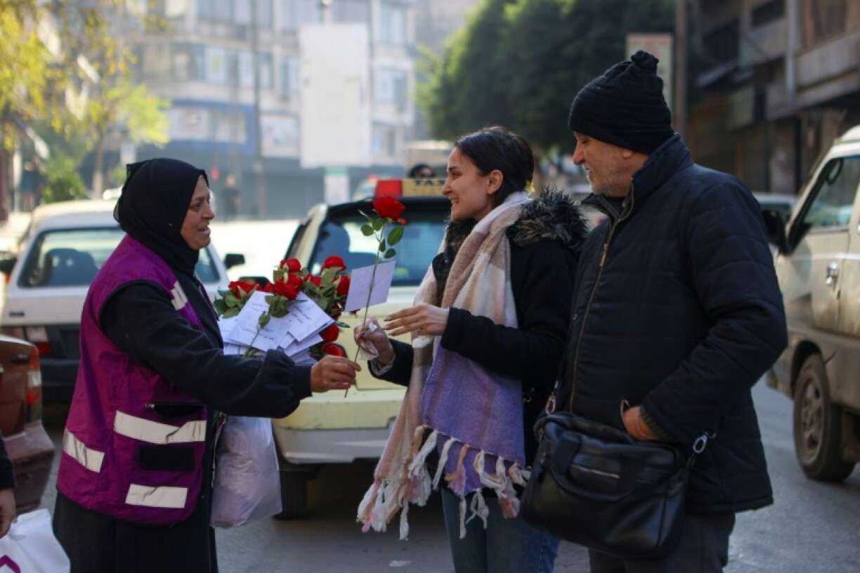 A woman offers a rose to a pedestrian in Aleppo, the first major city taken by rebels on their rapid push that ended with the fall of Bashar al-Assad's government