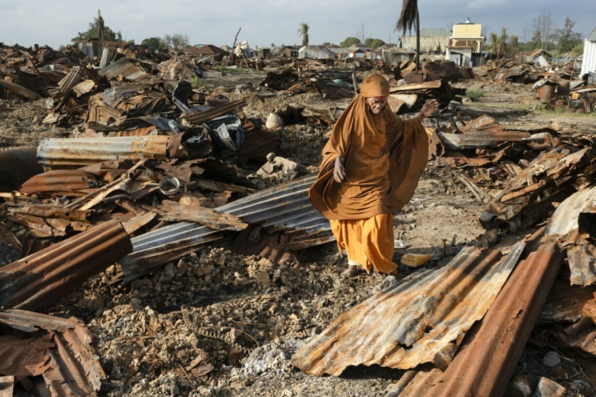 A woman salvages burnt iron sheets where her home was destroyed