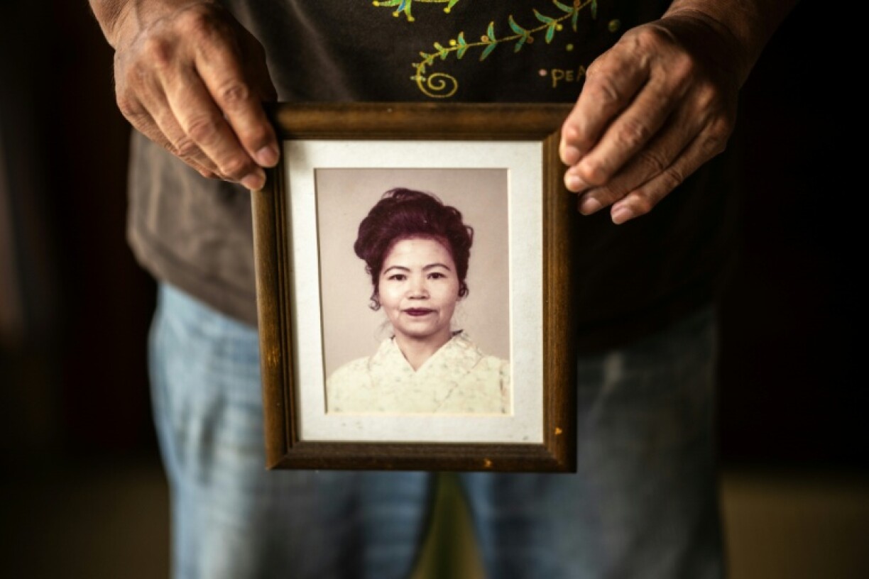 This photo taken on June 8, 2025 shows Takemasa Kinjo, who was a high school student when his mother was killed by a US Marine in 1974, holding her portrait during an interview with AFP