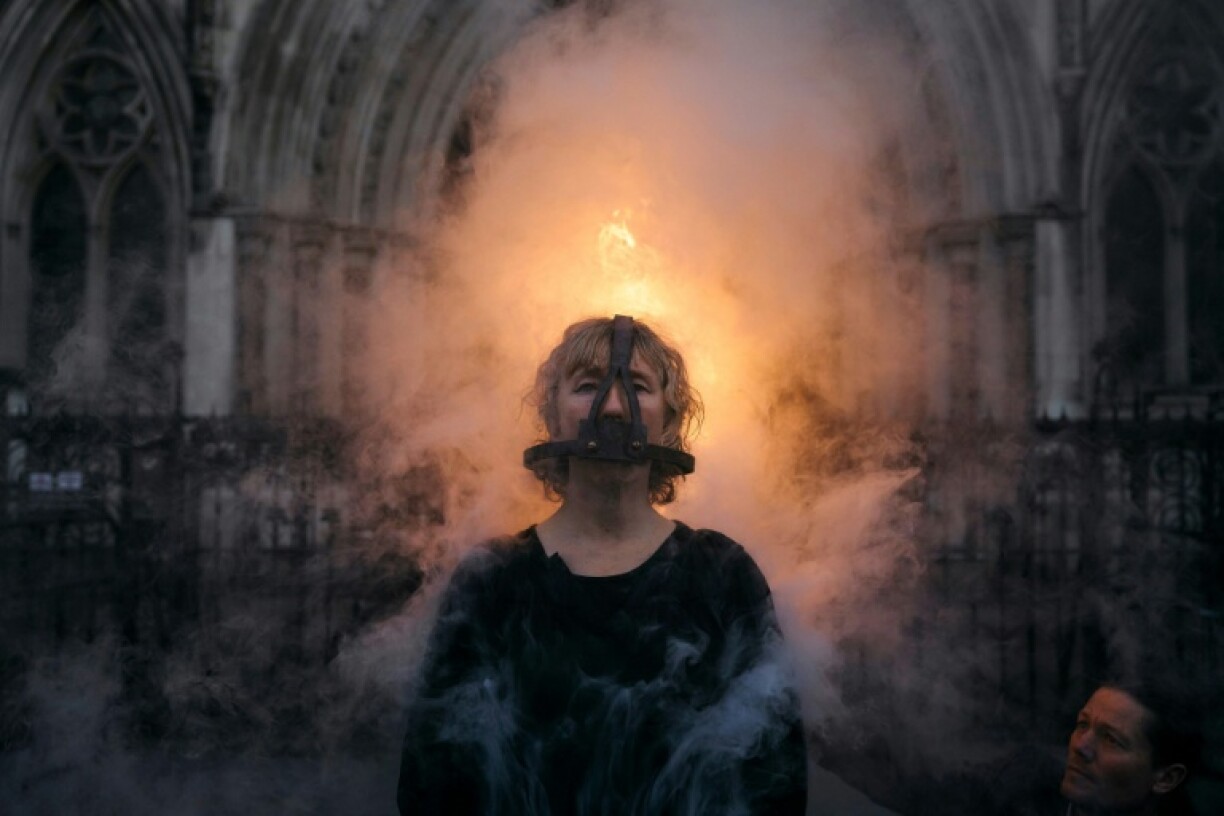 An activist from Ocean Rebellion wore a medieval torture device outside London's High Court