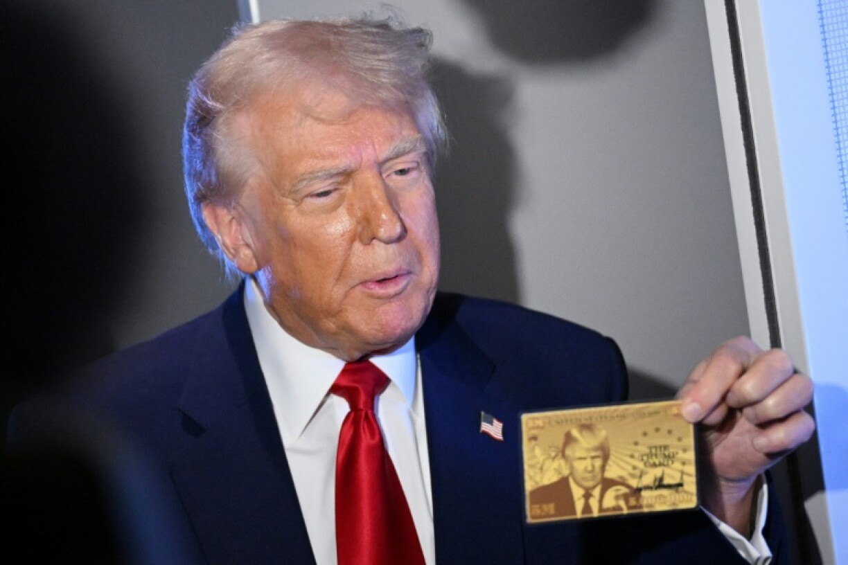 US President Donald Trump holds the $5 million dollar Gold Card prototype while speaking to reporters
