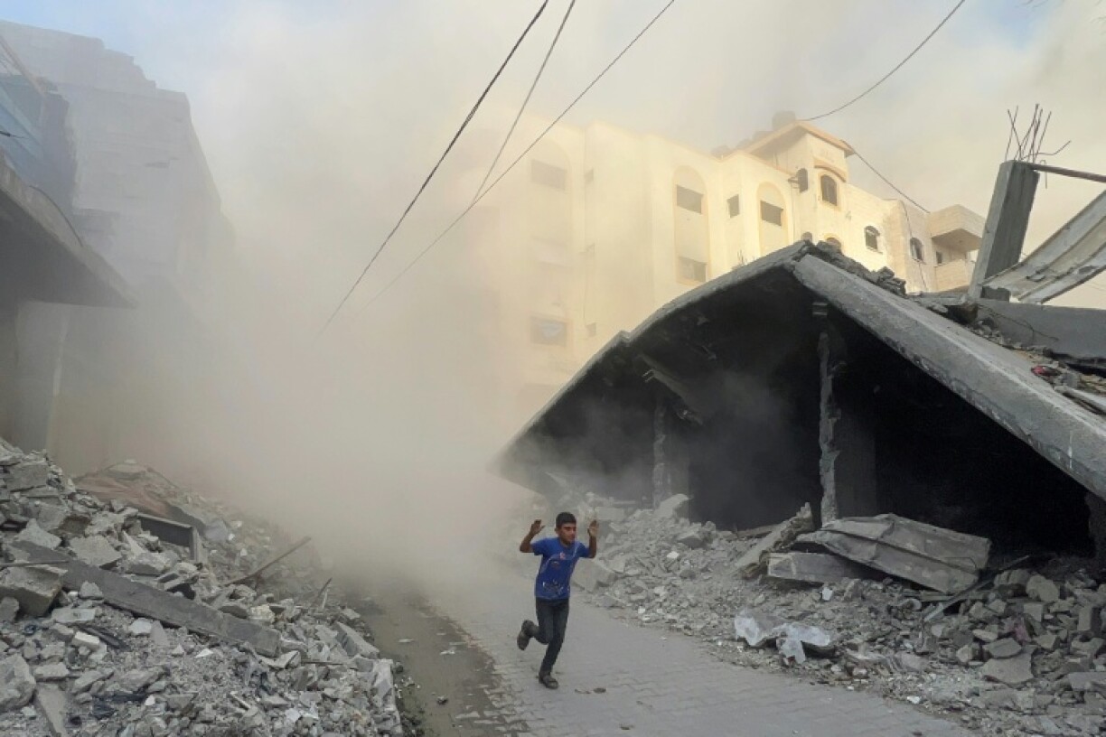 A Palestinian boy rushes away from the site of Israeli air strikes on a six-storey building in the Saftawi neighborhood west of Jabalia