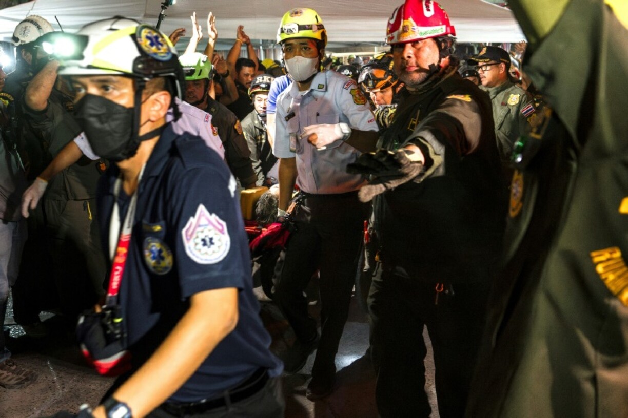 Rescue teams evacuate an injured man in a stretcher at a construction site where a building collapsed in Bangkok