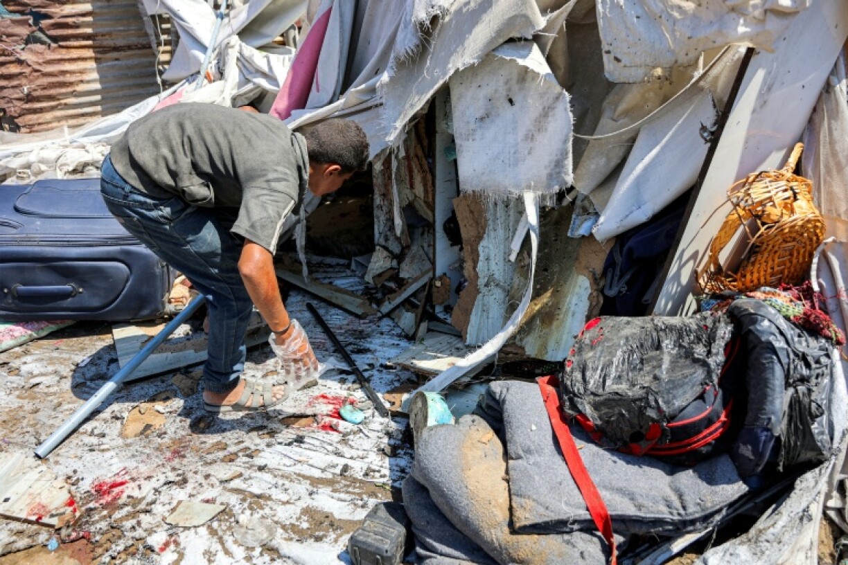 People inspect damage at a tent encampment hit by Israeli bombardment, in Gaza City