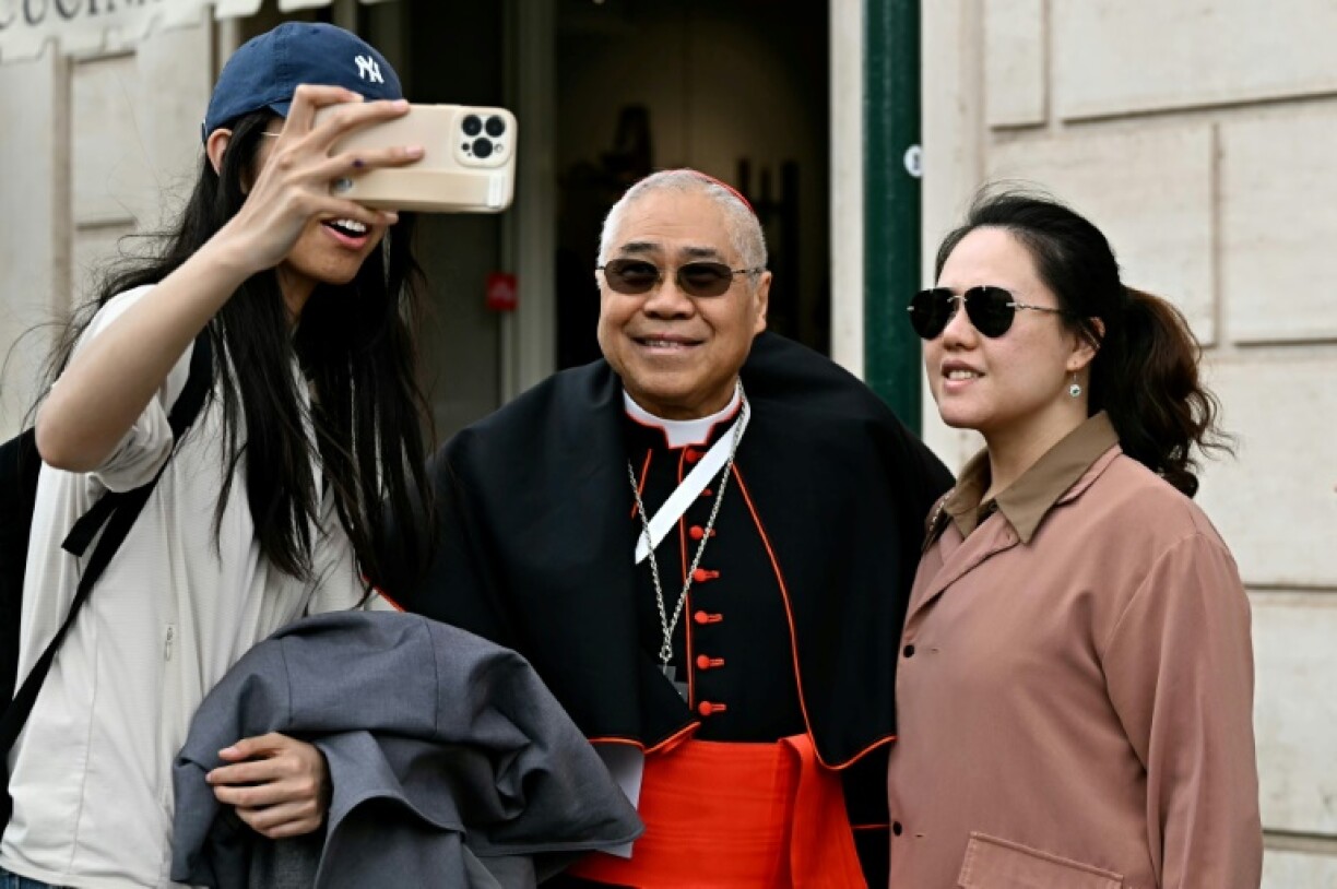 Archbishop of Singapore William Goh Seng Chye takes a selfie with tourists after a cardinals' meeting