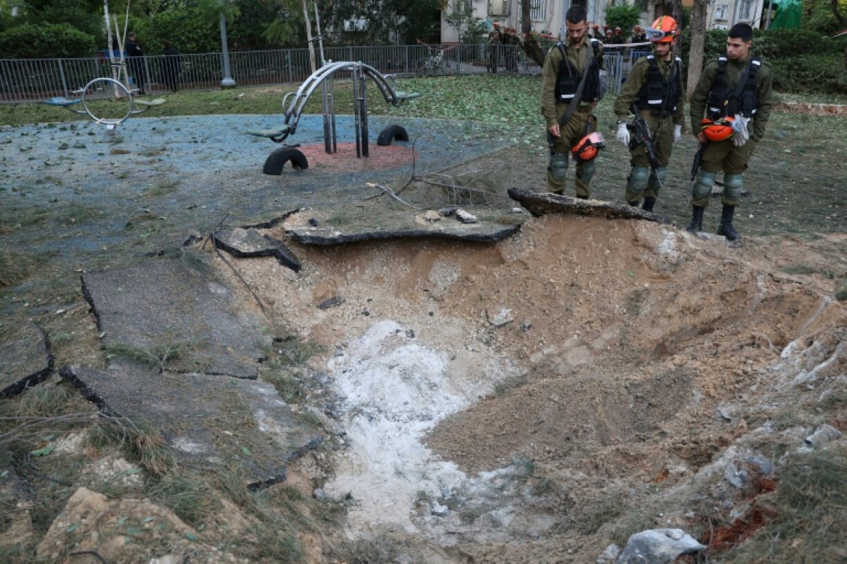 Israeli emergency responders inspect a crater at the site where a projectile fired from Yemen landed in Tel Aviv on December 21, 2024