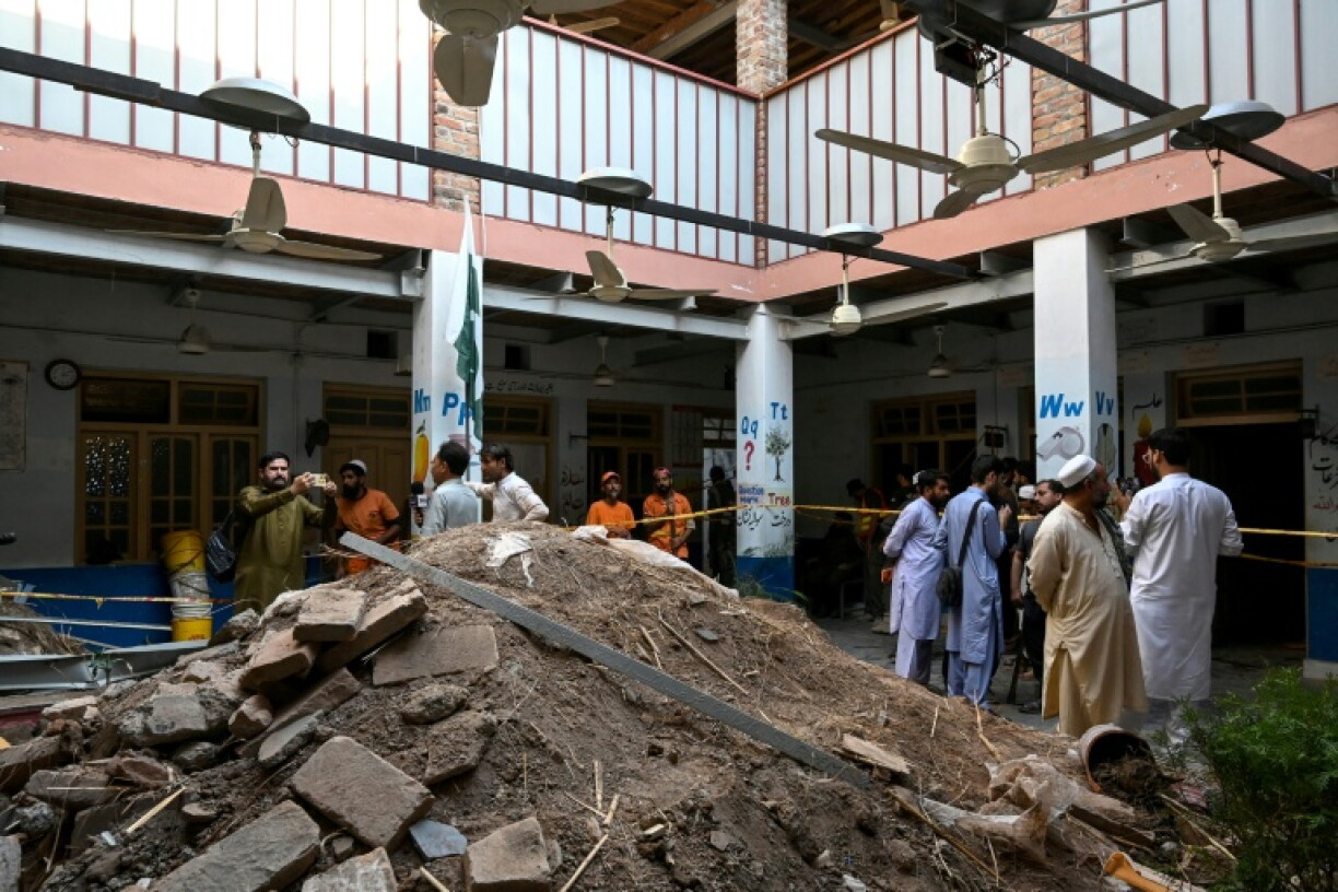 People gather around debris and rubble lying in the courtyard of the collapsed school