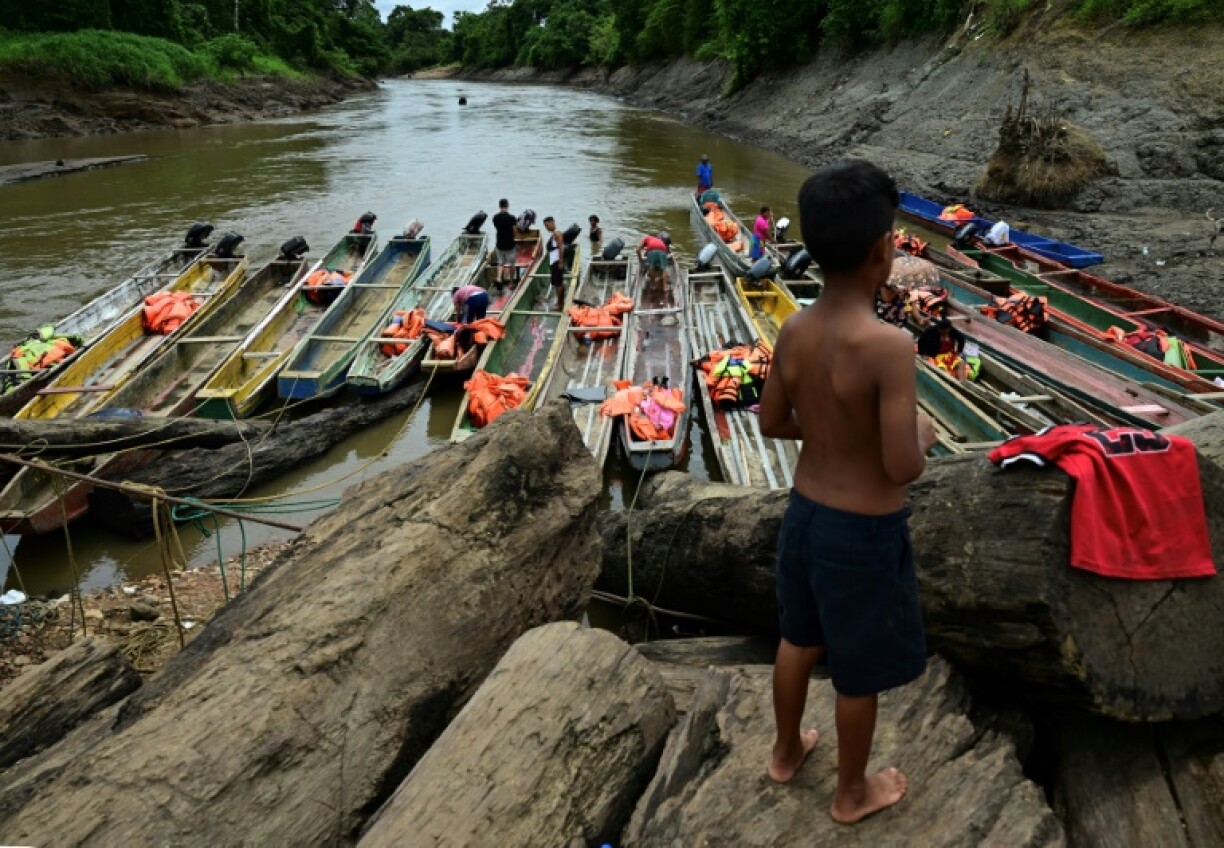 A child watches migrants cleaning boats at a temporary reception centre in Panama's Darien province