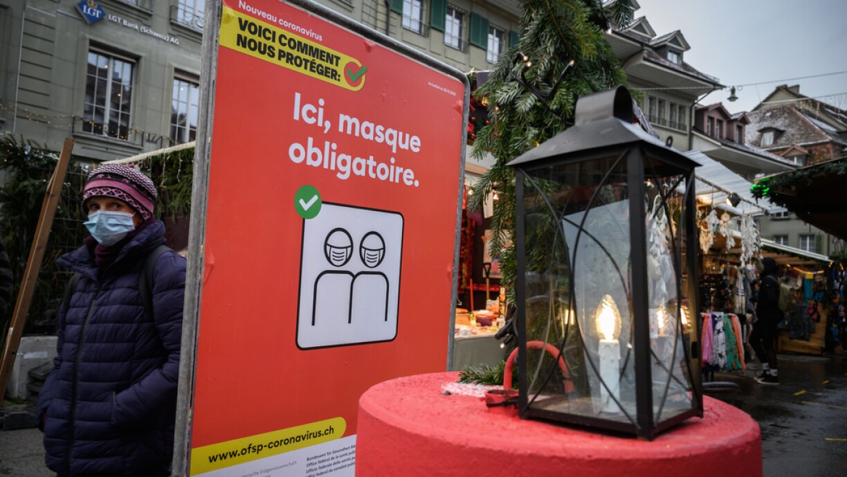 A woman wearing a disposable protective face mask walks past a placard reading in French
