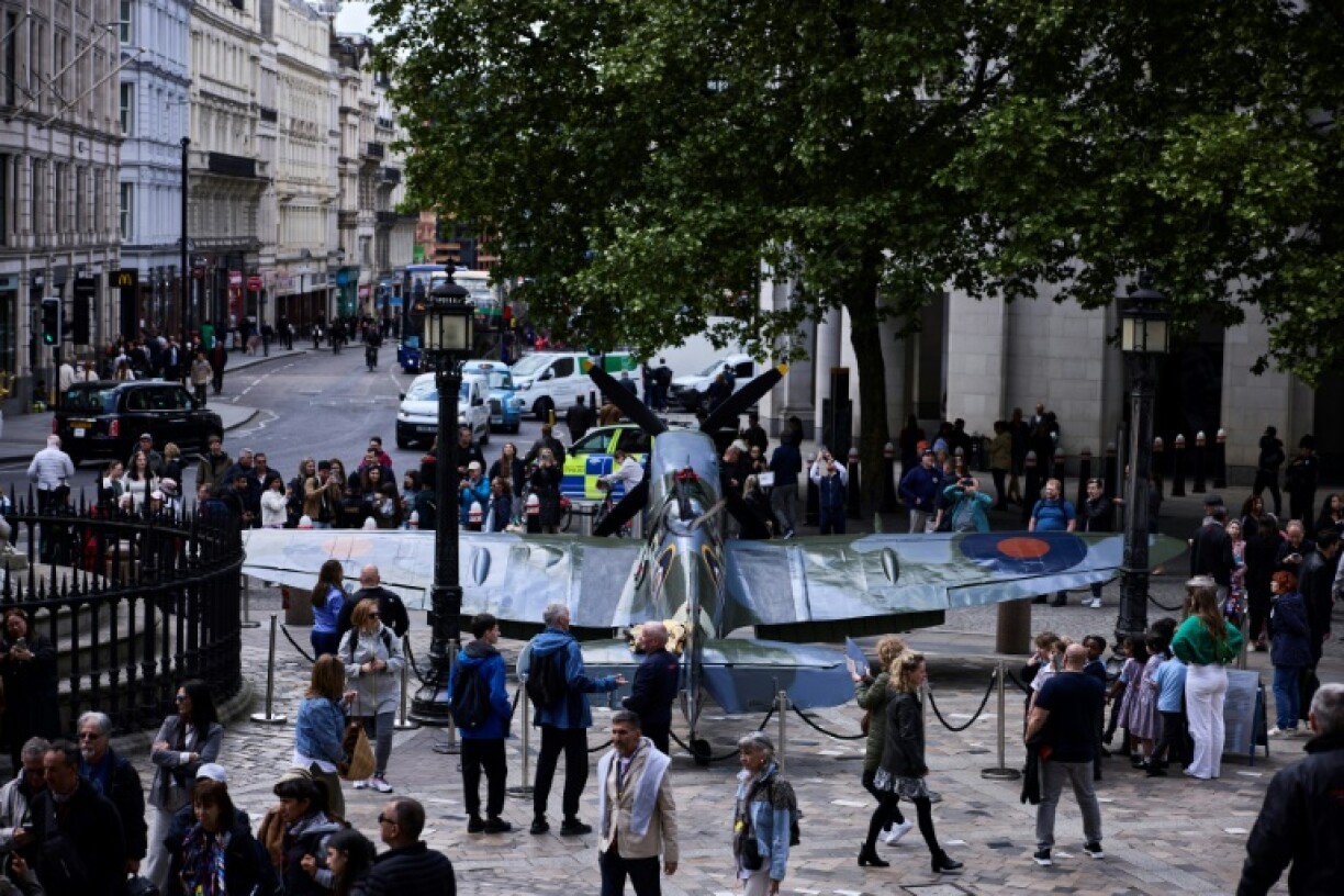 People walk past a replica Spitfire fighter plane outside St Paul's Cathedral in London ahead of a service to mark the 80th anniversary of Victory in Europe Day