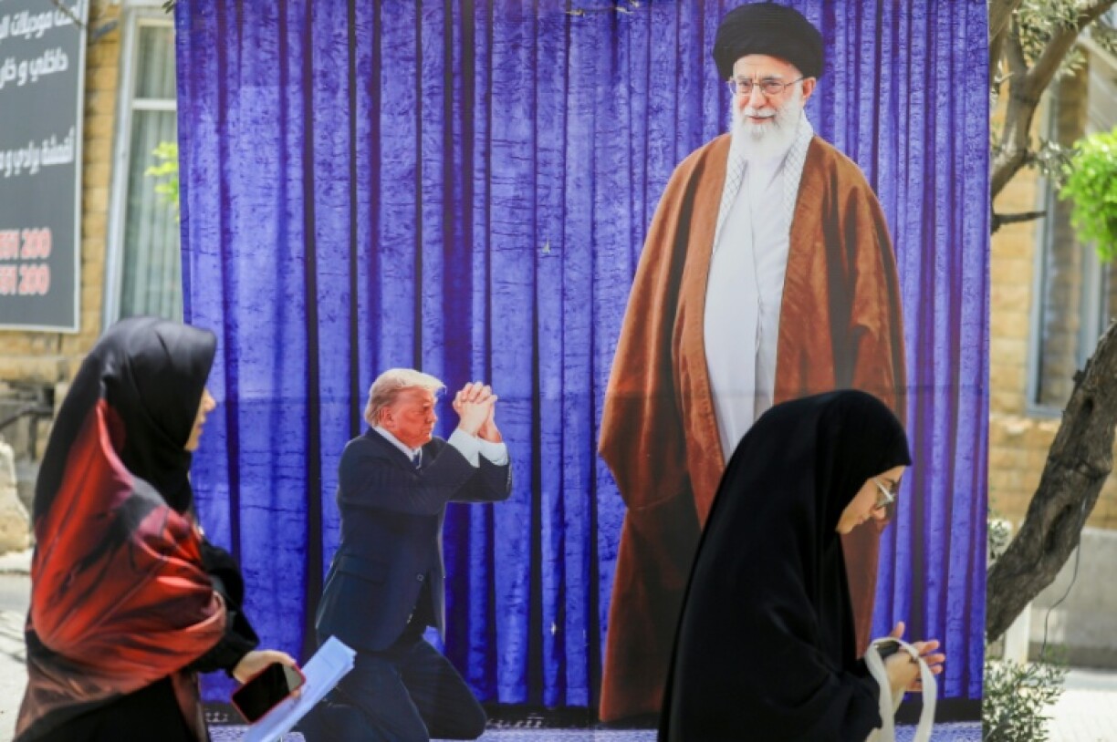 A poster depicting US President Donald Trump prostrating in front of Iran's Ayatollah Ali Kamenei hangs in a southern Beirut suburb