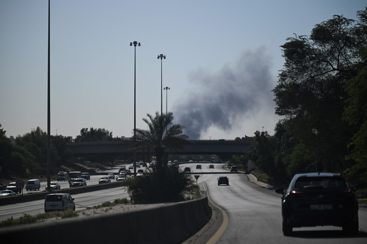Des automobilistes circulent dans une rue alors que de la fumée s'élève à la suite d'une attaque iranienne dans la zone où se trouve l'ambassade des États-Unis à Koweït City, le 2 mars 2026.