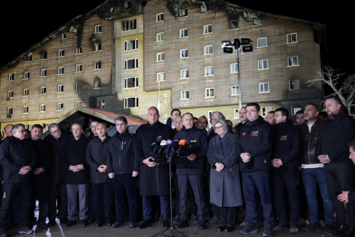 Le ministre turc de l'Intérieur, Ali Yerlikaya (C), s'adresse aux médias devant l'hôtel sinistré Grand Kartal, mercredi soir, dans la station de ski de Kartalkaya (centre de la Turquie)
