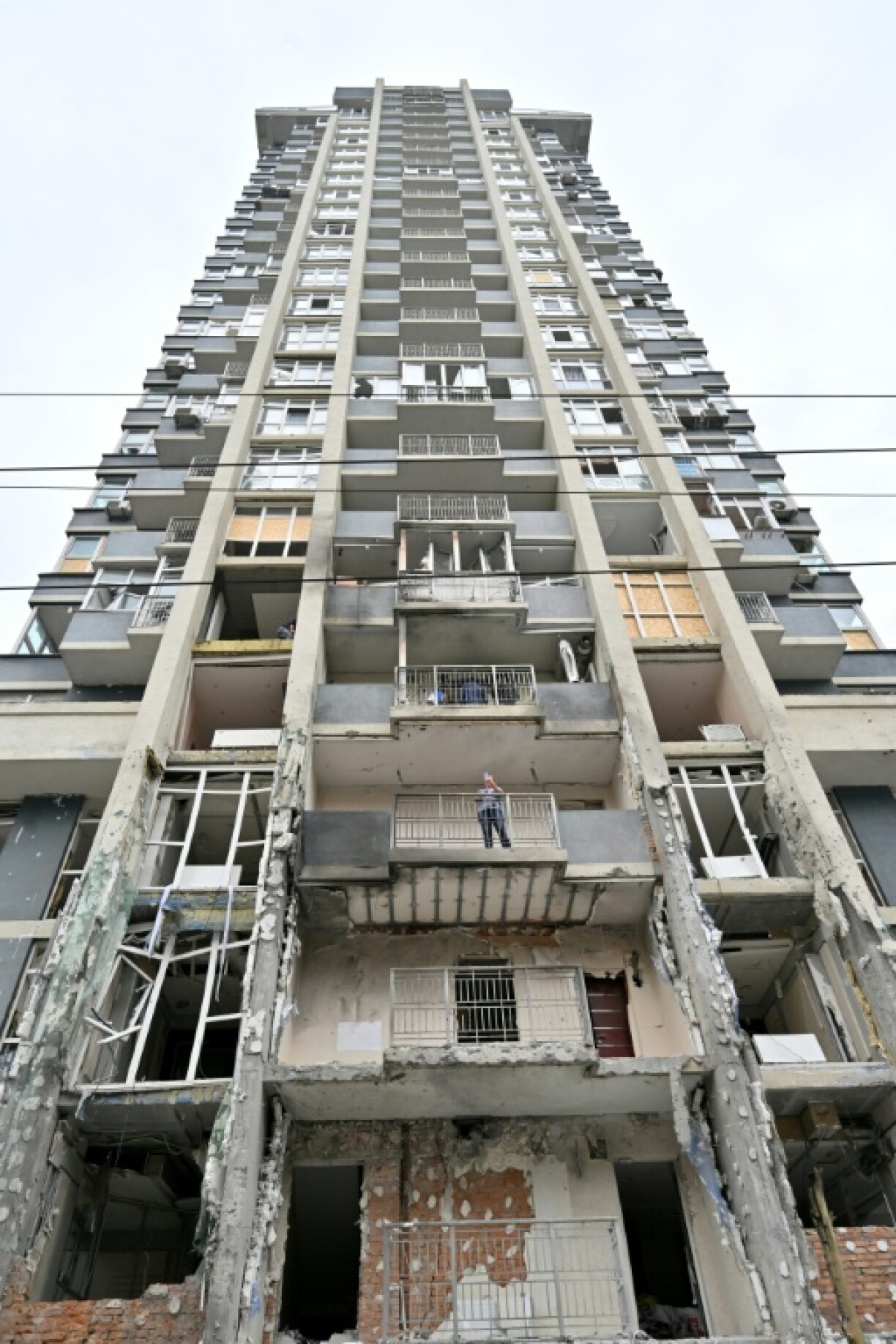 A resident stands on the terrace of a damaged flat following a drone strike in Kyiv
