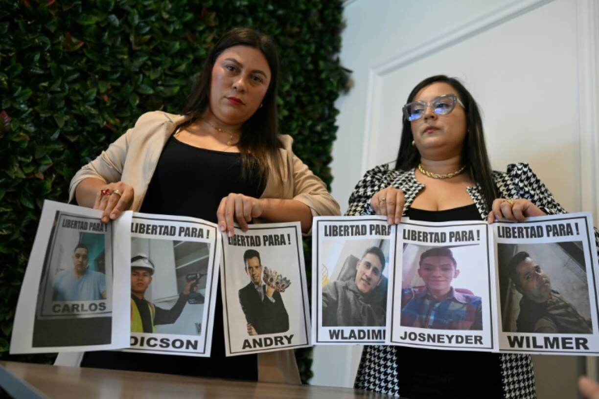 Reina Cardenas (L) and Jhoanna Sanguino hold pictures of Venezuelans deported from the United States to El Salvador