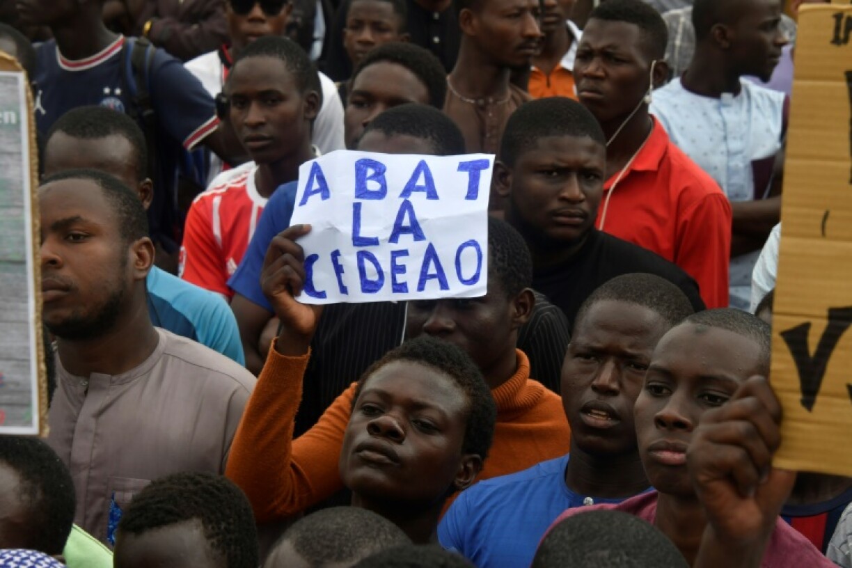 Des manifestations pro-putschistes brandissent une affichette dénonçant les menaces d'intervention de la Communauté économique des États de l’Afrique de l’Ouest (Cedeao), le 3 août 2023 à Niamey demonstration on independence day in Niamey on August 3, 2023. Security concerns built on August 3, 2023 ahead of planned protests in coup-hit Niger, with France demanding safety guarantees for foreign embassies as some Western nations reduced their diplomatic presence.