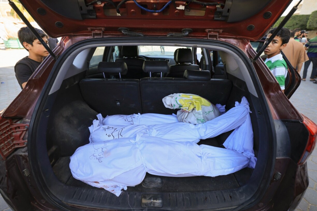 Les corps d'une famille déplacés sur la bande de Gaza après un bombardement, sous le regard d'enfants.