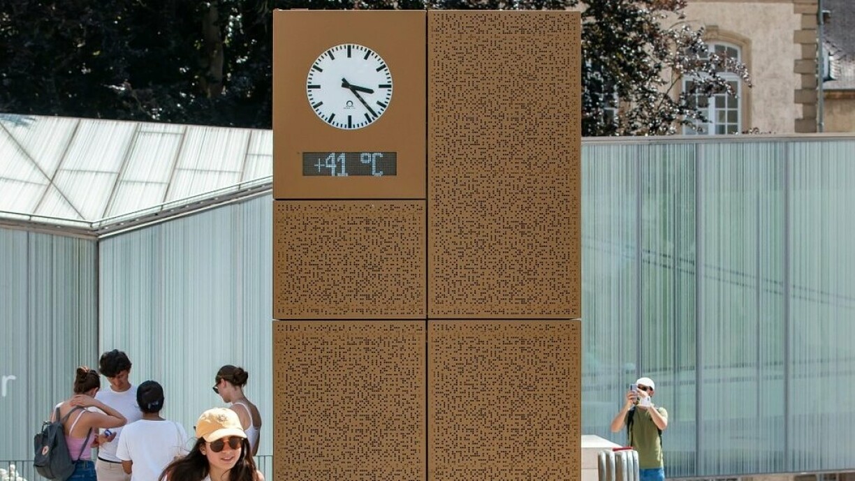 The clock on Place Guillaume II ticks over a 41°C sign.