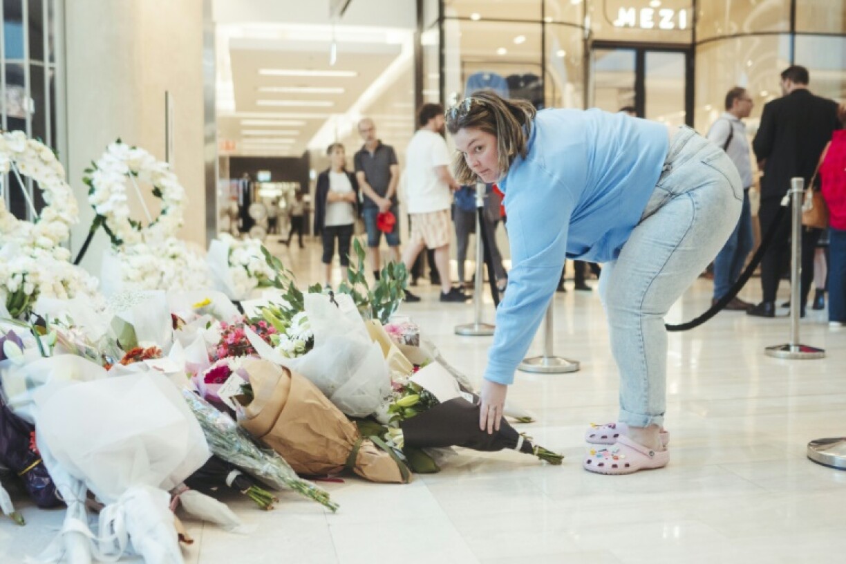 Une femme rend hommage aux victimes de l'attaque meurtrière du centre commercial Westfield Bondi Junction à Sydney lors de sa réouverture le 18 avril 2024, une semaine après le drame