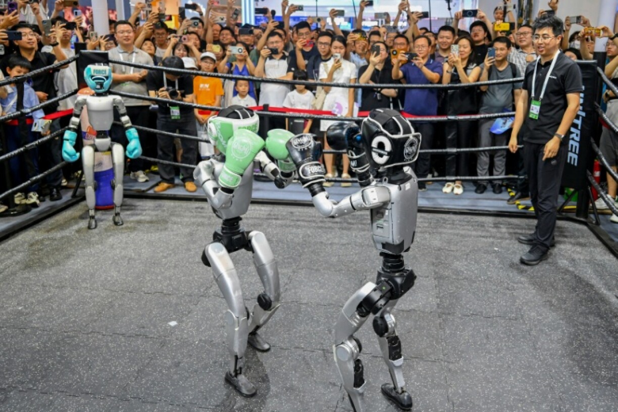 People watch humanoid robots boxing at an exhibition during the World AI Conference in Shanghai