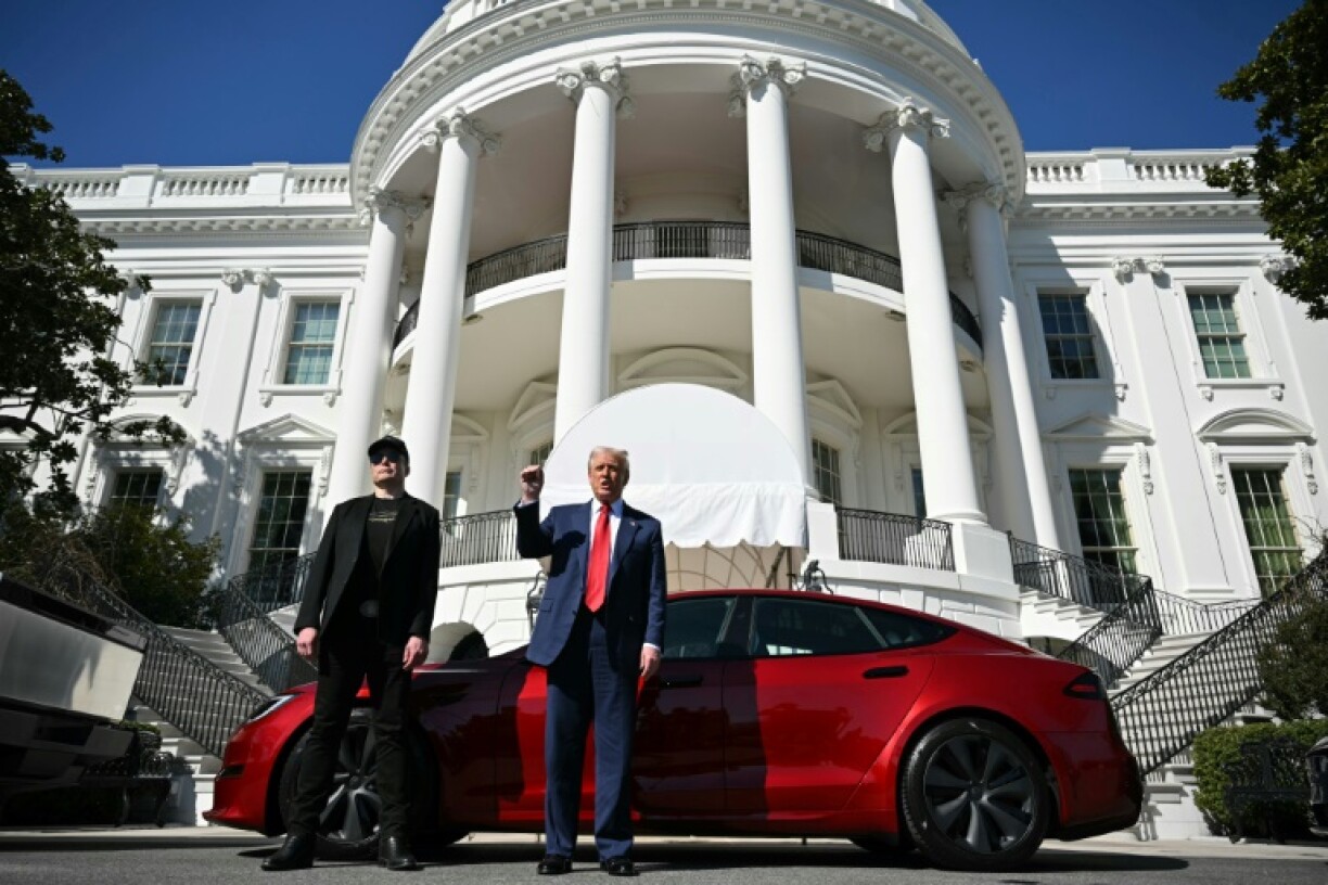 US President Donald Trump and Tesla CEO Elon Musk (L) speak to the press as they stand next to a Tesla vehicle at the South Portico of the White House